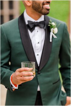 a man in a tuxedo holding a drink