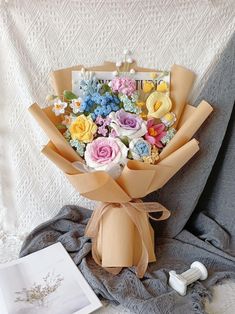 a bouquet of flowers sitting on top of a bed next to an open photo album