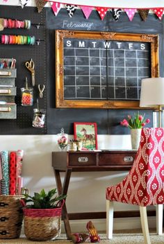 a desk and chair in front of a chalkboard with sewing supplies hanging on it