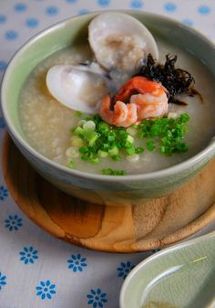 a bowl of soup with shrimp, scallops and rice on a wooden plate