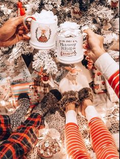 two people sitting on the floor in front of a christmas tree with presents and gifts