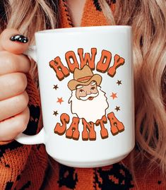 a woman wearing an orange sweater holding a white coffee mug with the words slow santa on it