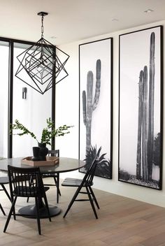 a dining room table with four chairs in front of two large cactus pictures on the wall