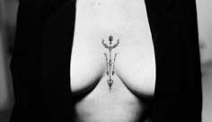 a black and white photo of a woman's breast with an arrow tattoo on it