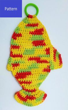 a crocheted fish ornament hanging from a green hook on a white surface