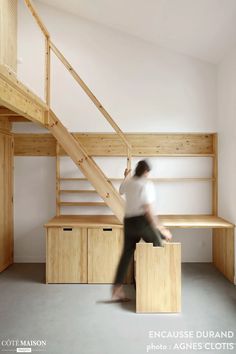 a woman is walking up the stairs in a room with wooden shelves and shelving