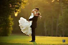 a bride and groom are dancing on the golf course in front of trees at sunset