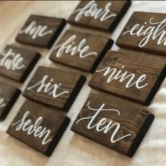 six wooden signs with the names of wine and ten written in white ink on them