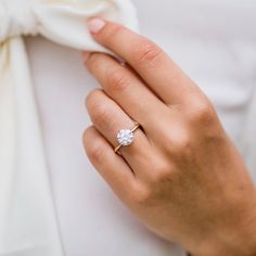 a woman's hand with a ring on it and a white bow around her neck