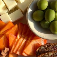 there are many different types of cheeses and fruit on the table, including bread