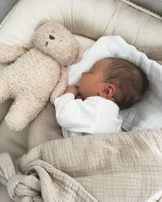 a baby sleeping in a crib next to a teddy bear