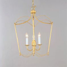 a gold chandelier with three candles hanging from the front and back ends, against a gray background