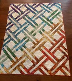 a multicolored quilt sitting on top of a wooden floor