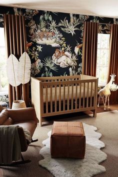 a baby's room with a crib, chair, ottoman and wallpaper