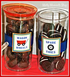 two glass jars filled with chocolate covered cookies and candy bar wrappers on top of a red table