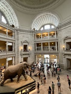 an elephant statue is in the middle of a large building with people standing around it