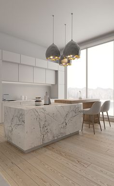 a large kitchen with marble counter tops and wooden flooring, along with two pendant lights hanging from the ceiling