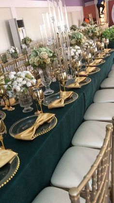 a long table is set up with gold and green place settings