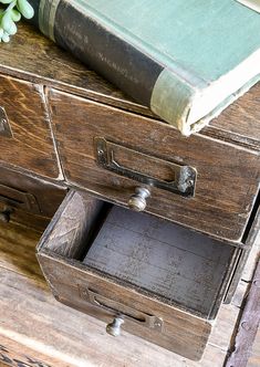 an old wooden dresser with two drawers and a book on top