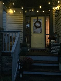 the front porch is lit up with christmas lights and wreaths on the door way