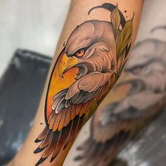 an eagle tattoo on the leg of a man with orange eyes and leaves around it