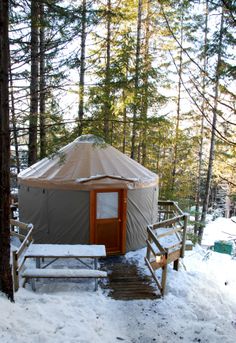 a yurt in the woods with snow on the ground and steps leading up to it