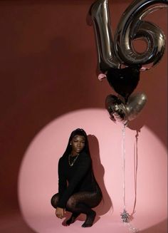 a woman sitting on the floor next to balloons