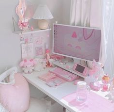 a white desk topped with a computer monitor next to a pink mouse pad and keyboard