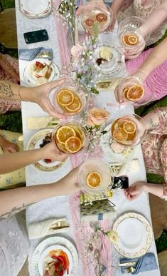 a group of people sitting at a table with plates and cups filled with orange slices