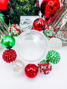 an assortment of glass christmas ornaments arranged in a circle on a white surface with one red and one green ornament