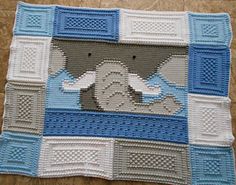 a crocheted blanket with an elephant in the center and blue, gray, white, and grey squares around it