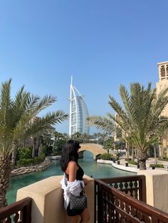 a woman is standing on a balcony looking at the water and palm trees in front of her