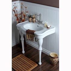 a white sink sitting on top of a wooden floor next to a bathtub and rug