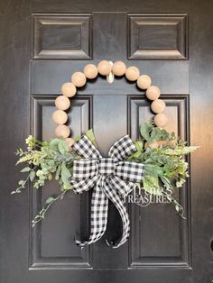 a black and white wreath with greenery on the front door