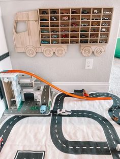 a toy train set is on the floor next to a play area with cars and trucks