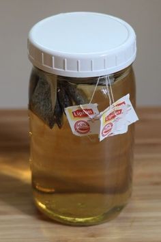 a glass jar filled with honey sitting on top of a wooden table next to a white tag