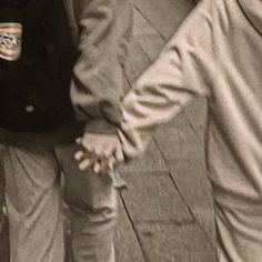 two people holding hands while walking down the street