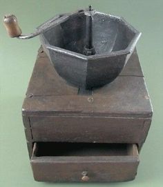 an old wooden box with a metal grinder on it's side and a pipe sticking out of the top