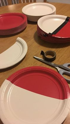 red and white plates are sitting on a table with scissors, tape, and pliers