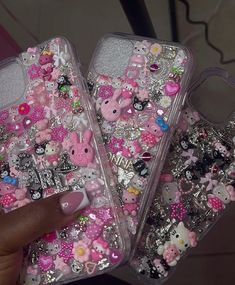 two clear cases with hello kitty and other items on them, one is holding a phone