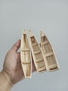 a hand holding three small wooden boats