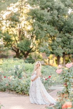 a pregnant woman standing in a garden with roses