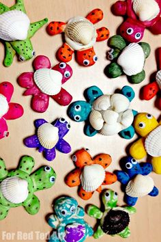 there are many different colored sea animals on the wooden table with shells and seashells