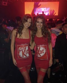 two beautiful women in red dresses standing next to each other at a party with coca - cola cans on their backs