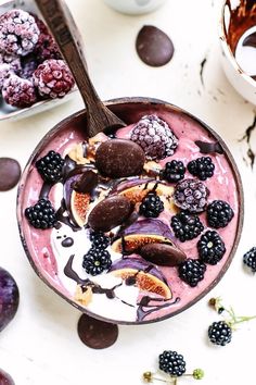 a bowl filled with fruit and yogurt on top of a white table next to other bowls