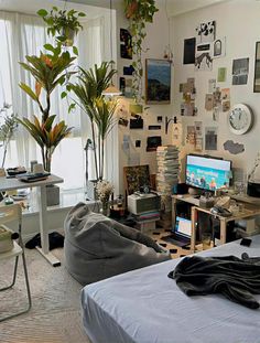 a living room filled with furniture next to a window covered in plants and pictures on the wall