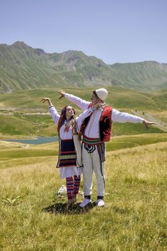 two people standing in the grass with their arms outstretched