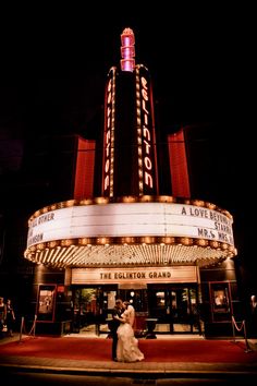 a bride and groom standing in front of the marquee at night