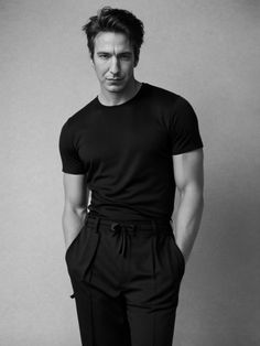 a man in black shirt and pants posing for the camera with his hands on his hips