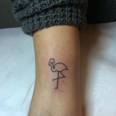 a small flamingo tattoo on the ankle is shown in black ink, and it looks like